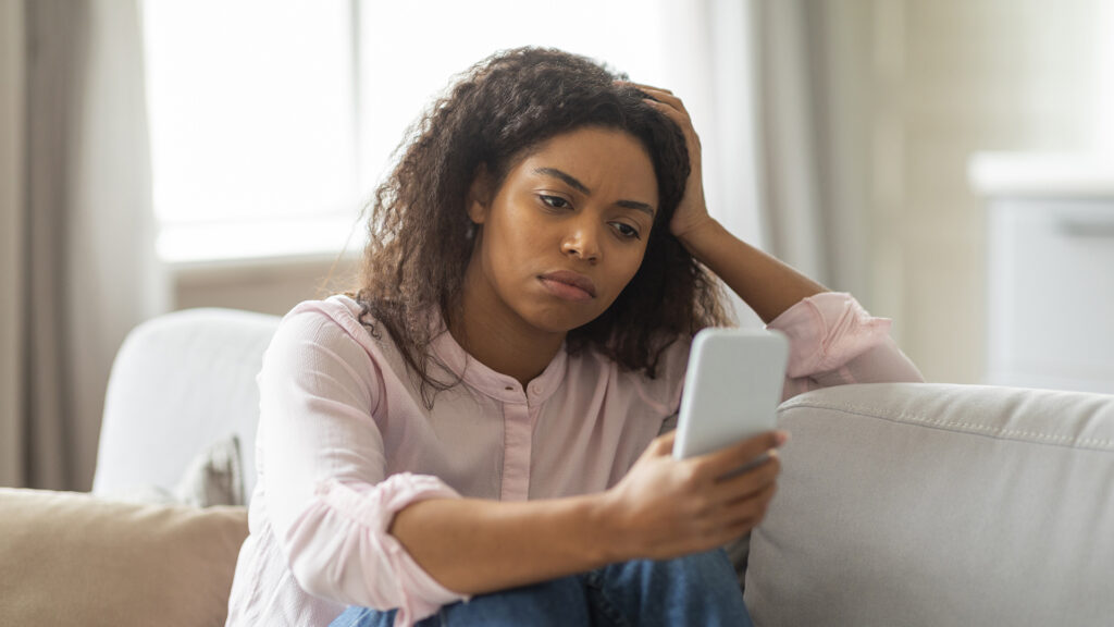 Young woman sadly looks at her phone
