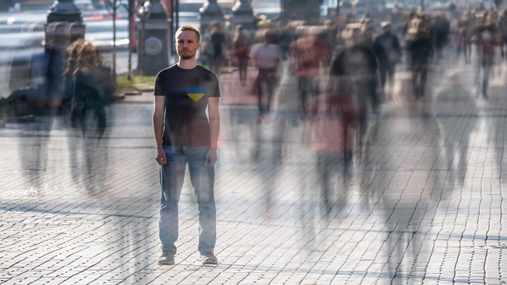 The young man stands in the middle of crowded street.